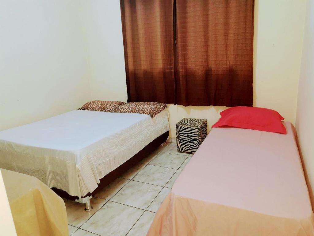 a room with two beds and a window at Casa amarela 02 jdm moema in Londrina