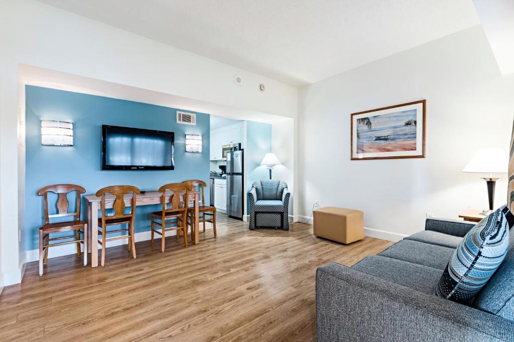 a living room with a couch and a table and chairs at The Atrium Resort by VSA Resorts in Virginia Beach