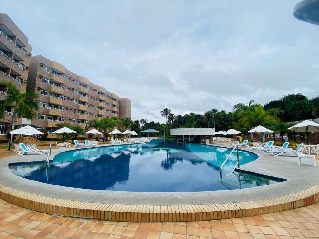 a large swimming pool with chairs and umbrellas at Gran Lençóis Flat Residence in Barreirinhas