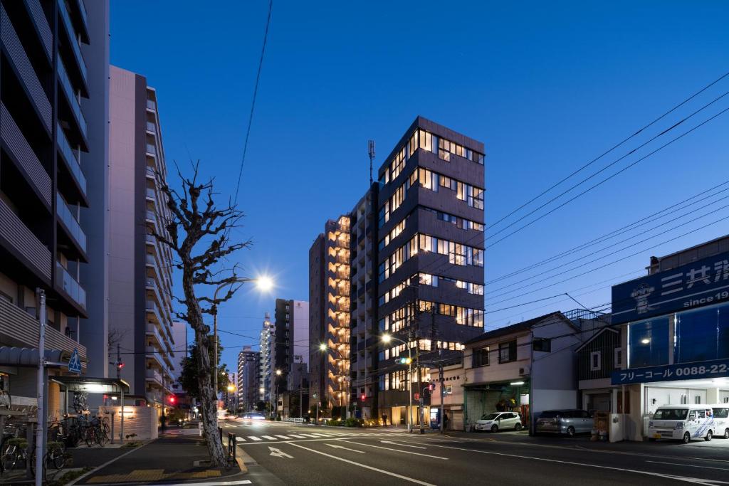 una calle de la ciudad por la noche con un edificio alto en PRISM INN OGU en Tokio