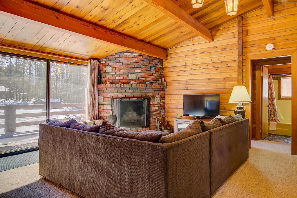 a living room with a large couch in front of a fireplace at Franconia Cabin Retreat in Franconia