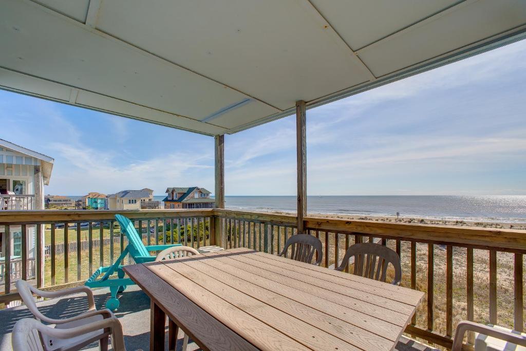 a deck with a wooden table and chairs and the beach at Skip 713 RR in Rodanthe