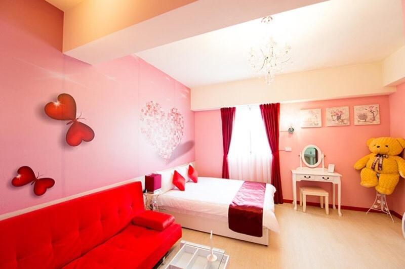 a bedroom with a teddy bear and a red couch at Yizhong Street Hechen in Taichung