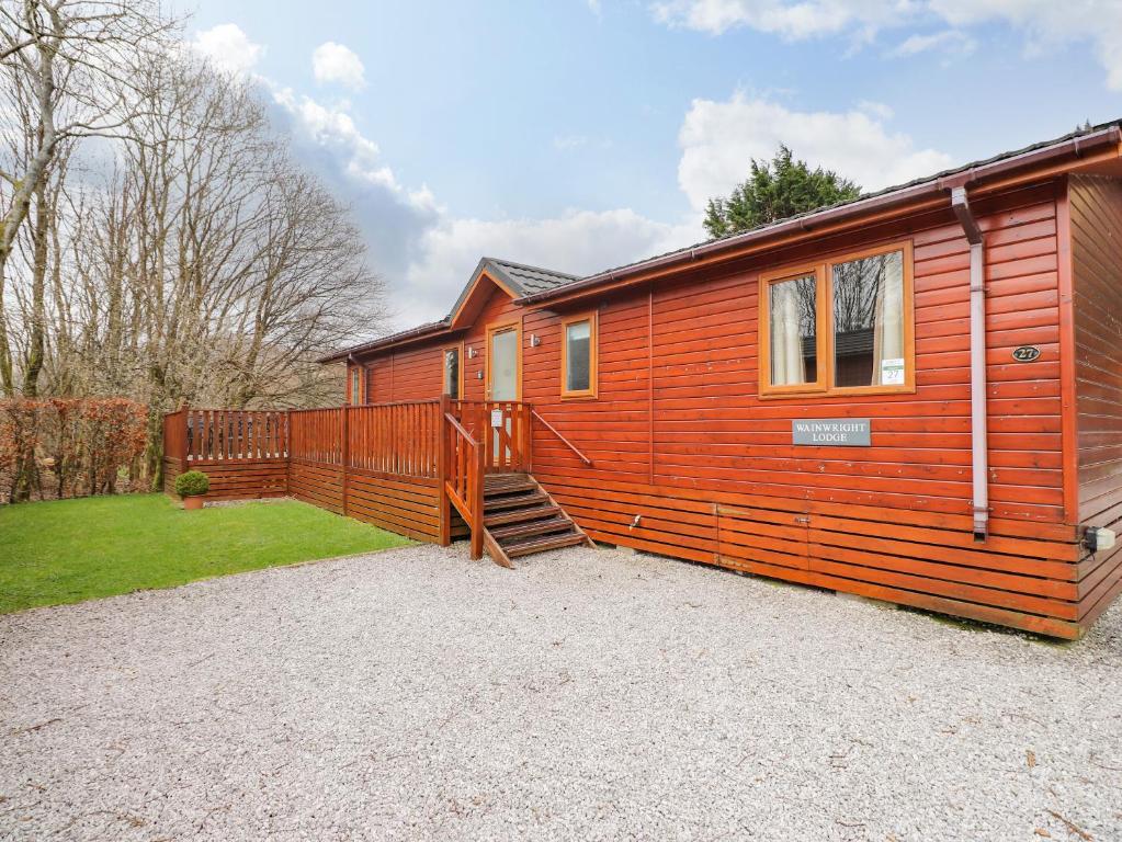 a large wooden cabin with a large deck at Wainwright Lodge in Windermere
