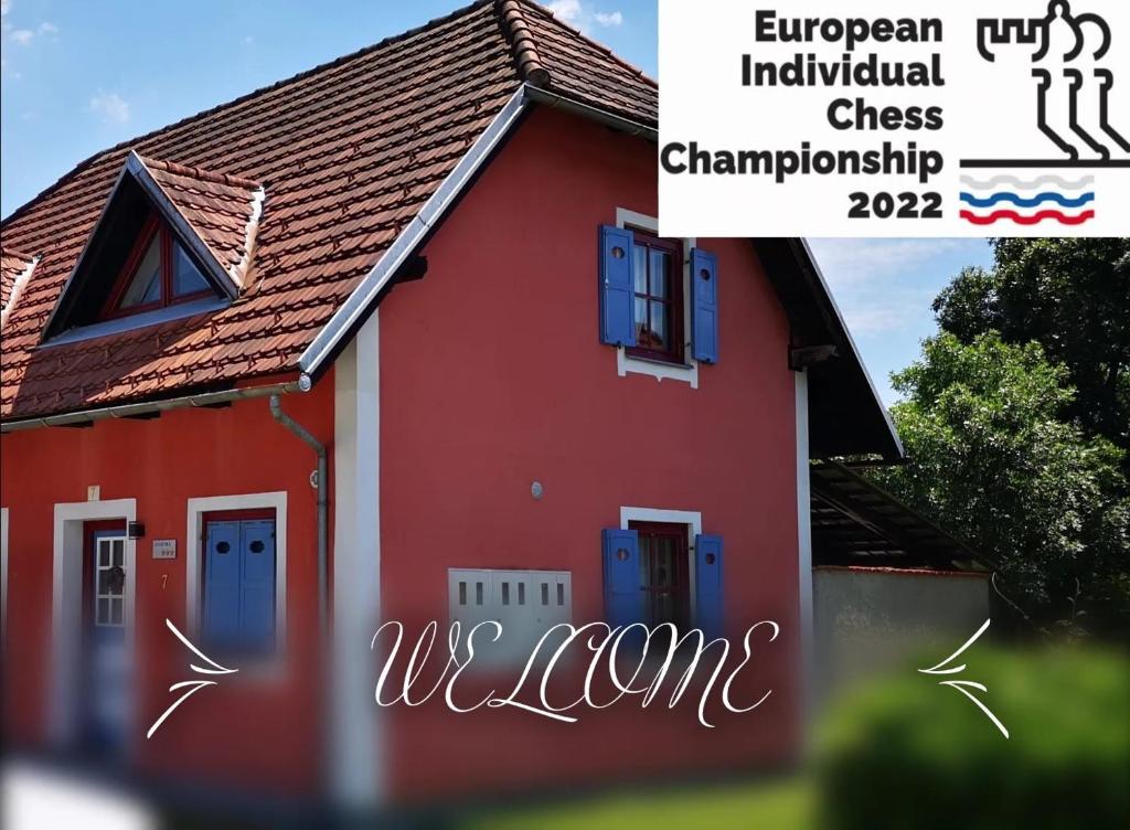 une maison rouge avec des portes bleues et les mots championnat urbain d'échecs individuels dans l'établissement Terme Catez Apartment 7, à Čatež ob Savi