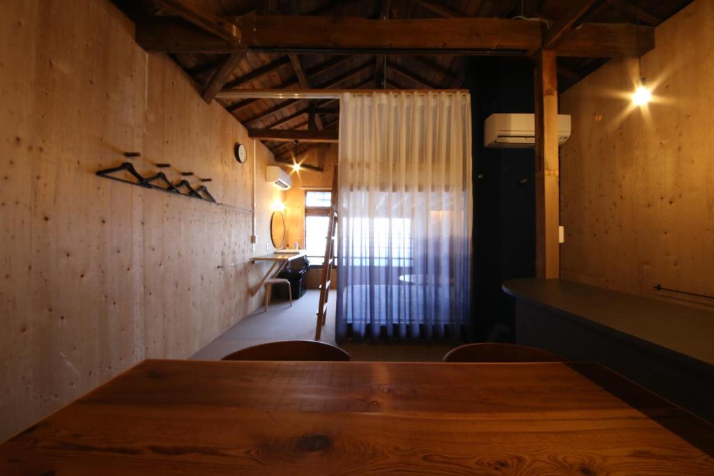 uma sala de jantar com uma mesa de madeira e cadeiras em まちの別邸 緝 shu em Kochi