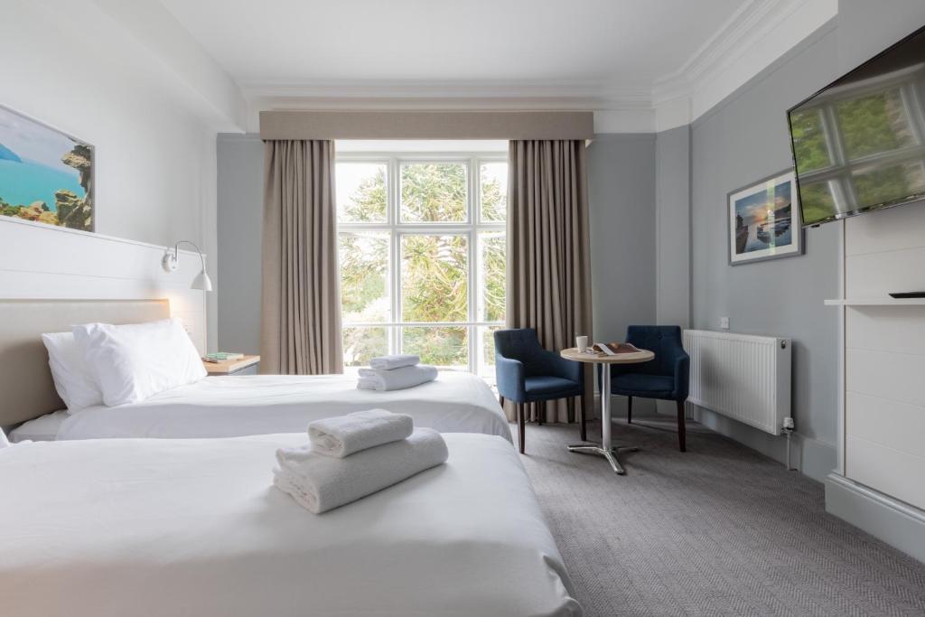 um quarto de hotel com duas camas e uma janela em The Valley of Rocks Hotel em Lynton