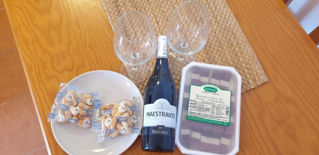 a table with a bottle of wine and a plate of cookies at Apartamentos Atlanterra COSTA Y SOL in Zahara de los Atunes