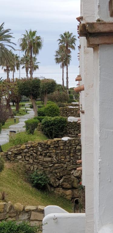 a stone wall next to a building with palm trees at Apartamentos Atlanterra COSTA Y SOL in Zahara de los Atunes