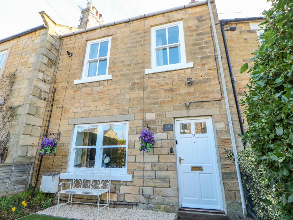 una vieja casa de ladrillo con una puerta blanca en Elm Cottage en Bishop Auckland