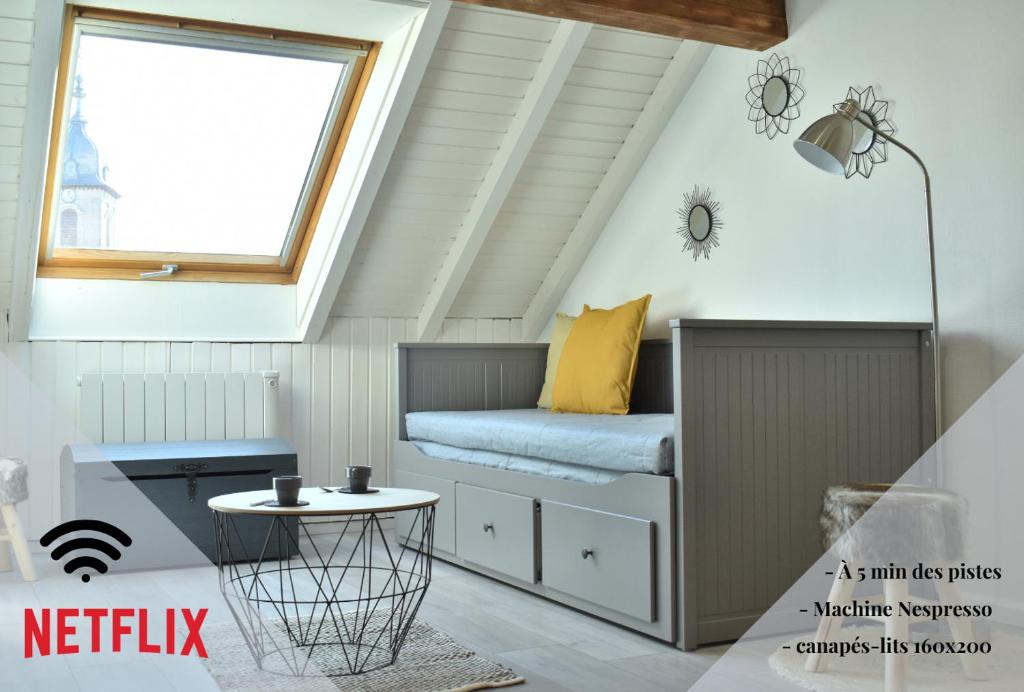 a bed in a attic with a window at Charmant studio, le petit gris des montagnes in Mouthe