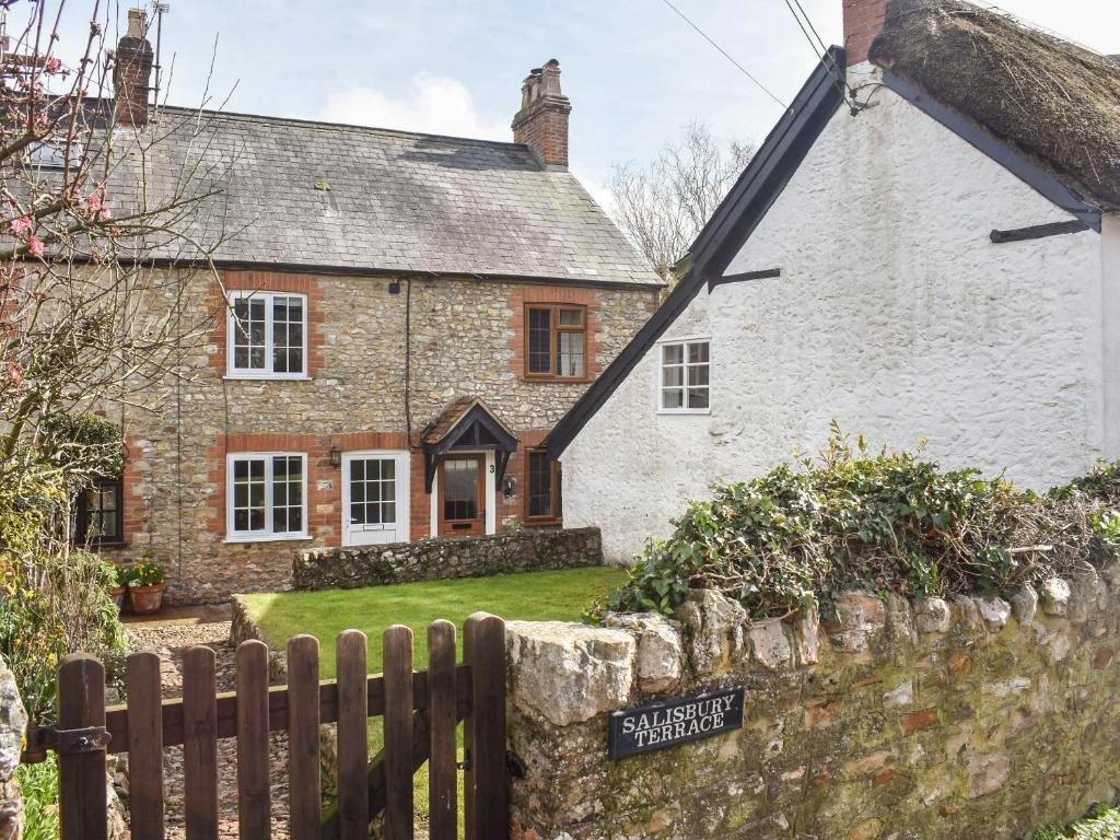 a stone house with a fence in front of it at Jasmine Cottage in Axminster