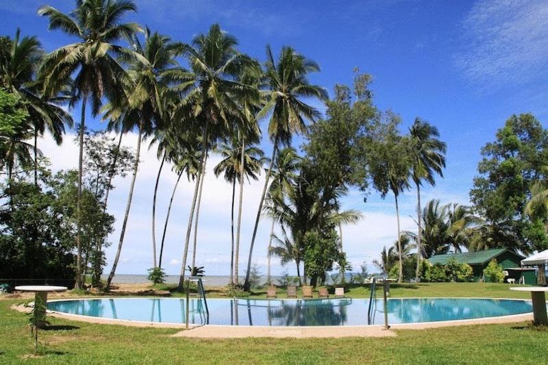a resort swimming pool with palm trees in the background at Langkah Syabas Beach Resort in Kinarut
