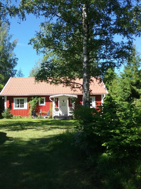 una casa roja con un árbol en el patio en Björkslingan, en Vimmerby