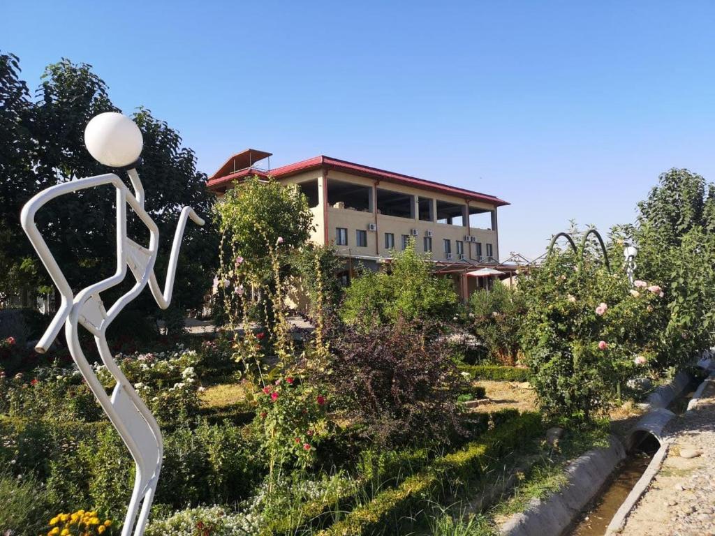 a house in the background with a statue in a garden at Uzumfermer Hotel & Winery in Tashkent