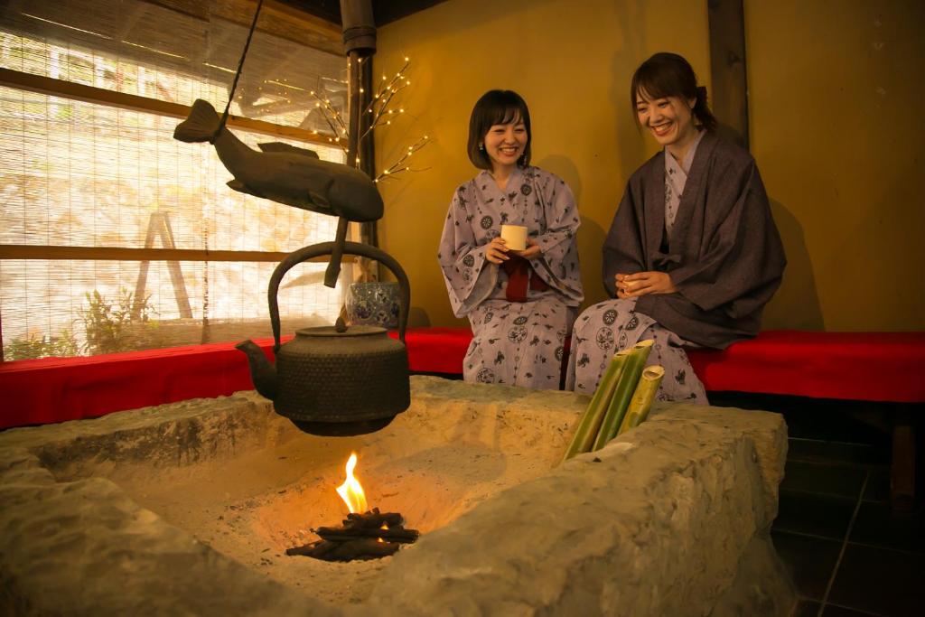 two women are sitting next to a fire pit at Yumerindo in Minamioguni
