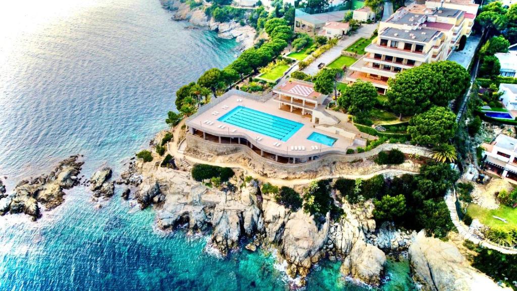 an aerial view of a house on a cliff next to the water at Almadraba Park Hotel in Roses