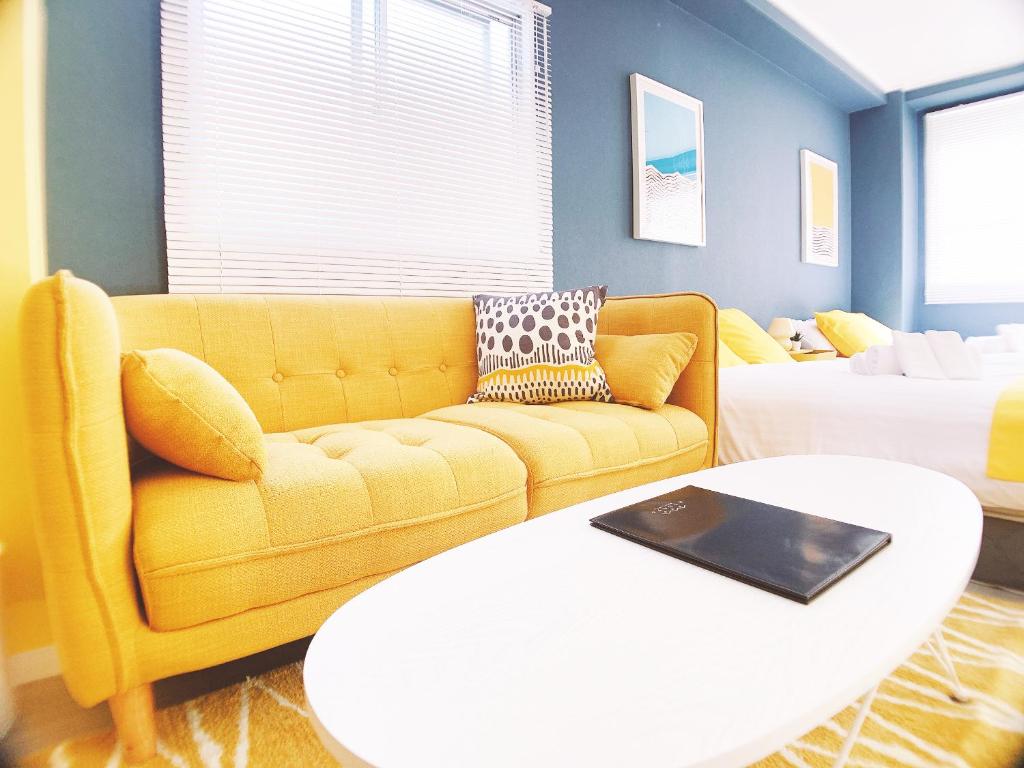 a living room with a yellow couch and a table at OUCHI HOTEL Nagarekawa with Dogs in Hiroshima