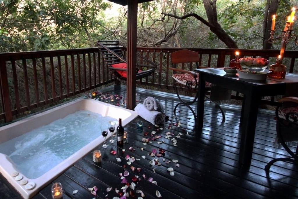 a hot tub on a deck with a table at Thulamela Couples Retreat in Hazyview