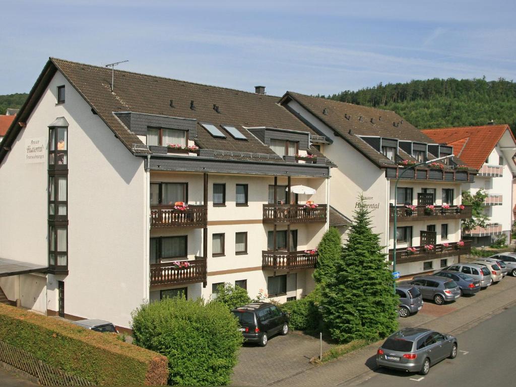 ein großes weißes Gebäude mit Autos auf einem Parkplatz in der Unterkunft Pension Huttental in Bad Soden-Salmünster