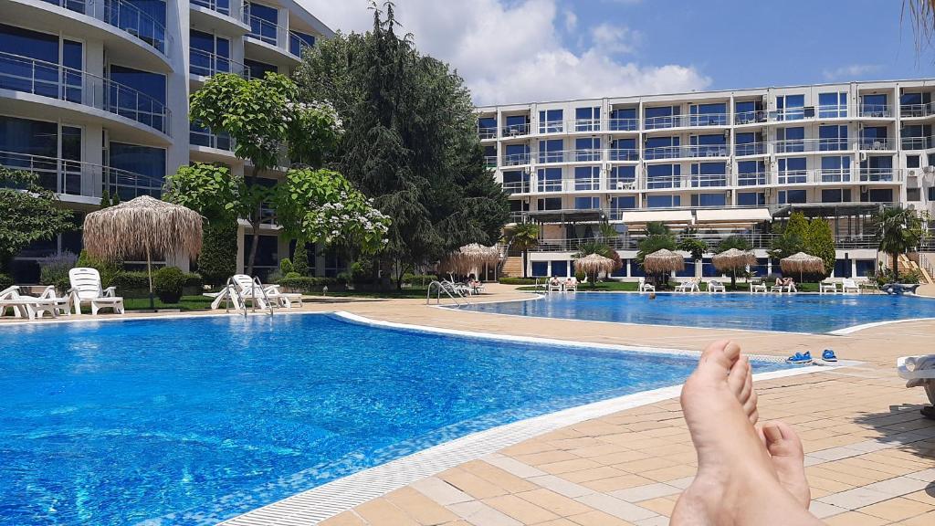 a person laying in front of a hotel swimming pool at Decor in Atlantis Resort&SPA by RV Apartments in Burgas City