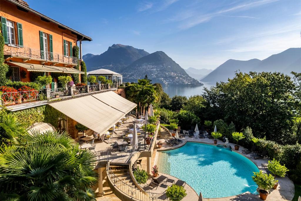 a view of a resort with a swimming pool and mountains at Villa Principe Leopoldo - Ticino Hotels Group in Lugano