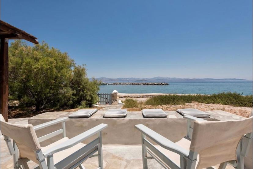 a group of chairs sitting on a patio near the ocean at Aqua Apartment in Kampos Paros