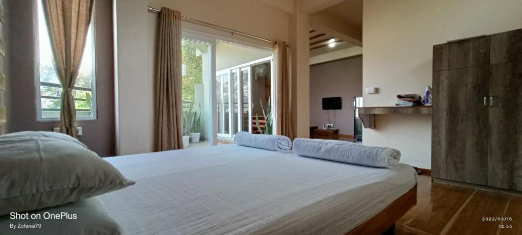 a large bed in a bedroom with a large window at Deluxe Room Zobawm Homestay in Āīzawl