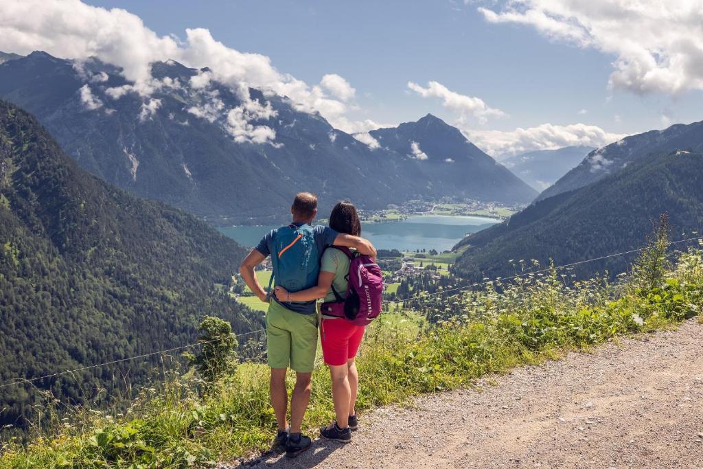 a man and woman standing on a dirt road looking at mountains at Verwöhnhotel Kristall in Pertisau