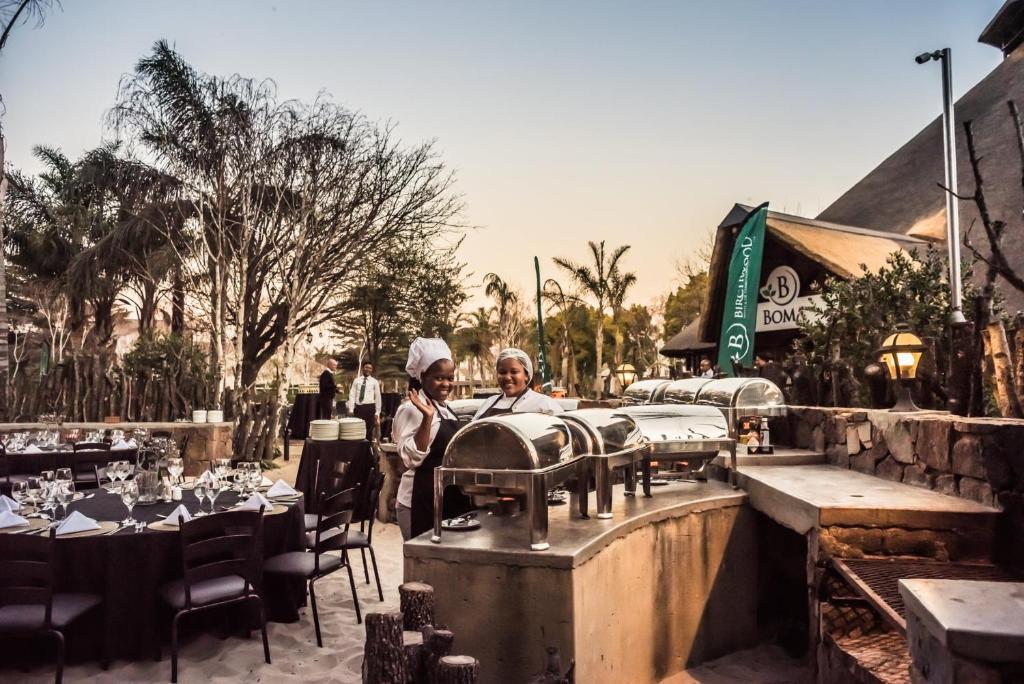 dos personas de pie frente a un restaurante con mesas en Birchwood Hotel and OR Tambo Conference Centre en Boksburg