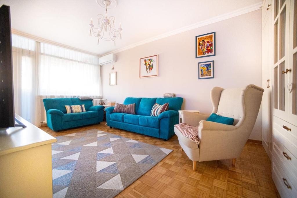 a living room with a blue couch and two chairs at Sava Centar 1-bedroom apartment in the heart of New Belgrade in Belgrade