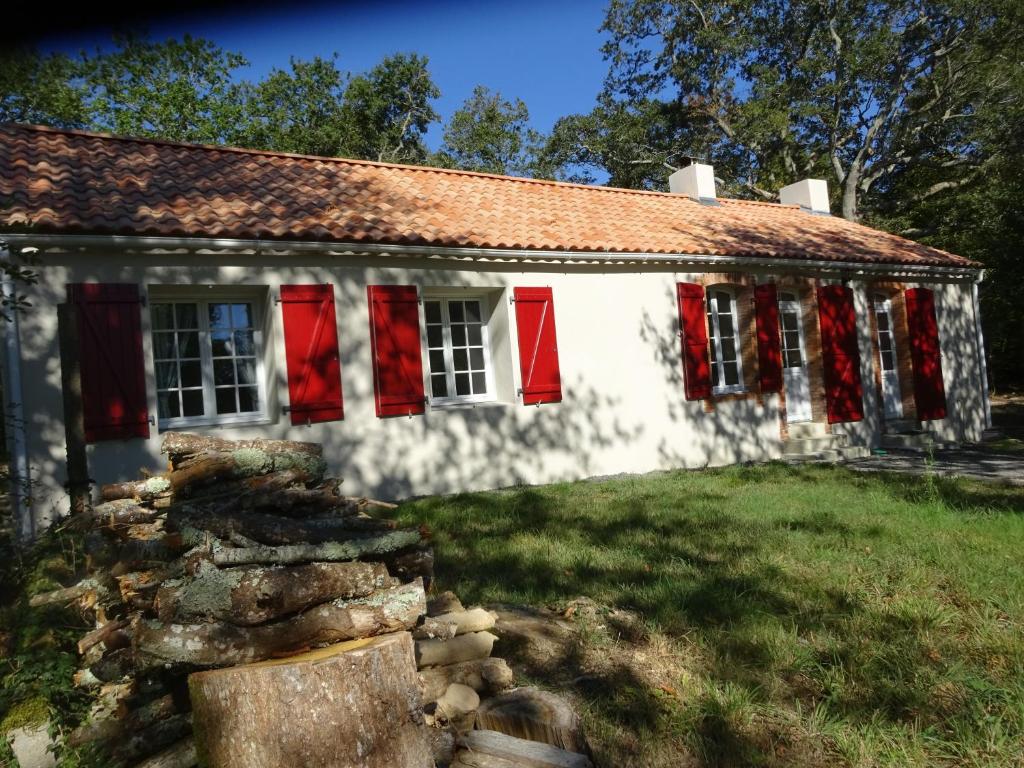 una antigua casa blanca con ventanas de contraventanas rojas en Rénovation proche lac et mer, en Landevieille