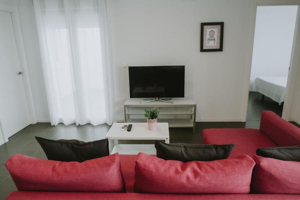 a living room with a red couch and a tv at Apartamentos ZHR 2 in Zahara de los Atunes