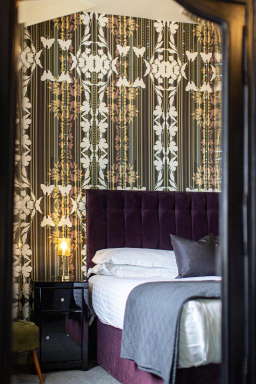 a bedroom with a bed with a purple headboard at Escape Boutique B&B in Llandudno