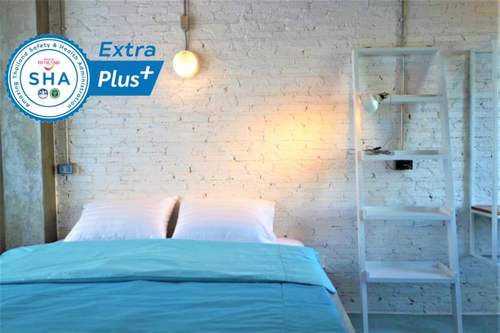 Un dormitorio con una cama azul y una pared de ladrillo blanco en Chanchalay Hip Hostel SHA Extra Plus, en Krabi