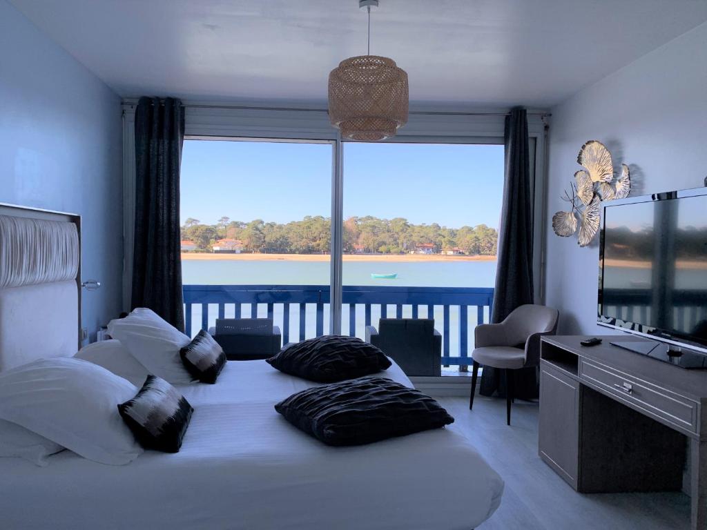 a bedroom with a bed with a large window at Le Relais Du Lac in Hossegor