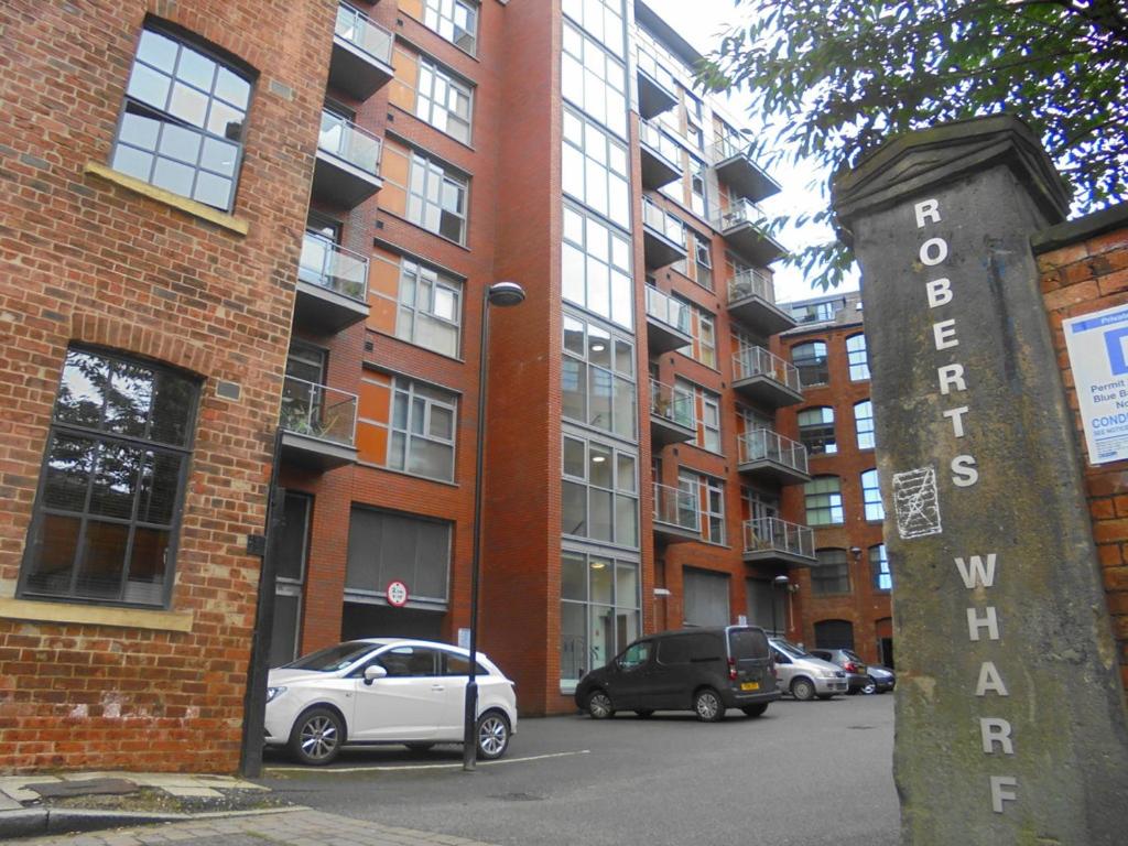 a parking lot with cars parked in front of a brick building at Neptune Apartments in Leeds