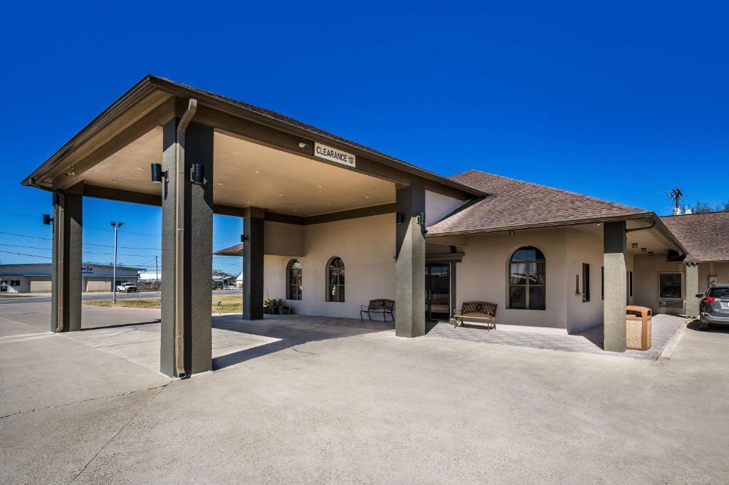 a building with a garage with a parking lot at SureStay Hotel by Best Western Alice in Alice