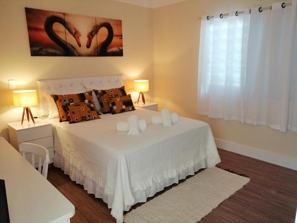 a bedroom with a large white bed with two lamps at Apartamento Aconchegante de luxo da Elena in São Carlos