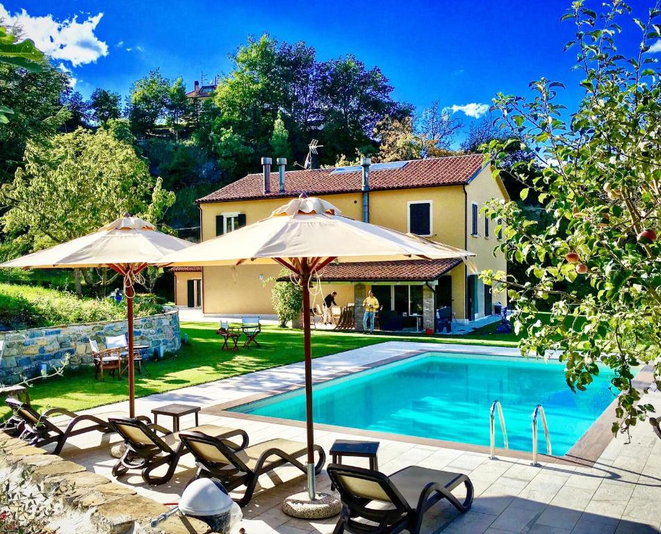 a pool with chairs and umbrellas next to a house at Tenuta Borgio in Venarotta