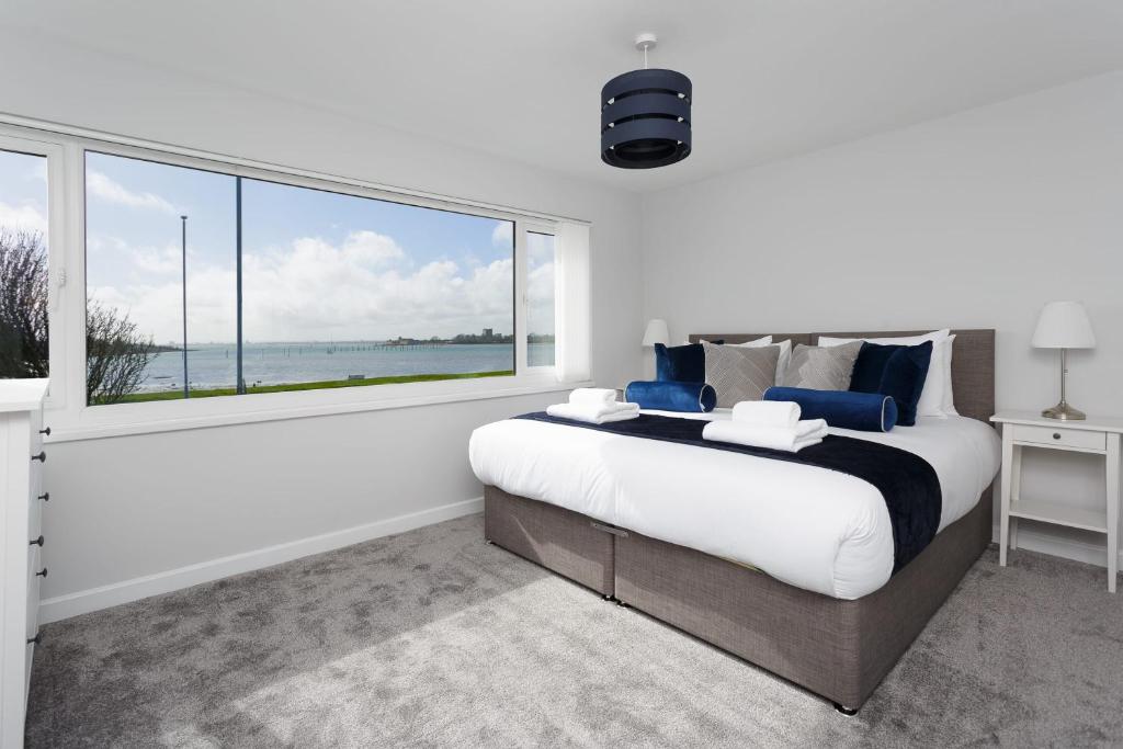ein Schlafzimmer mit einem großen Bett und einem großen Fenster in der Unterkunft Castle View - Port Solent Stunning Waterfront House in Portsmouth