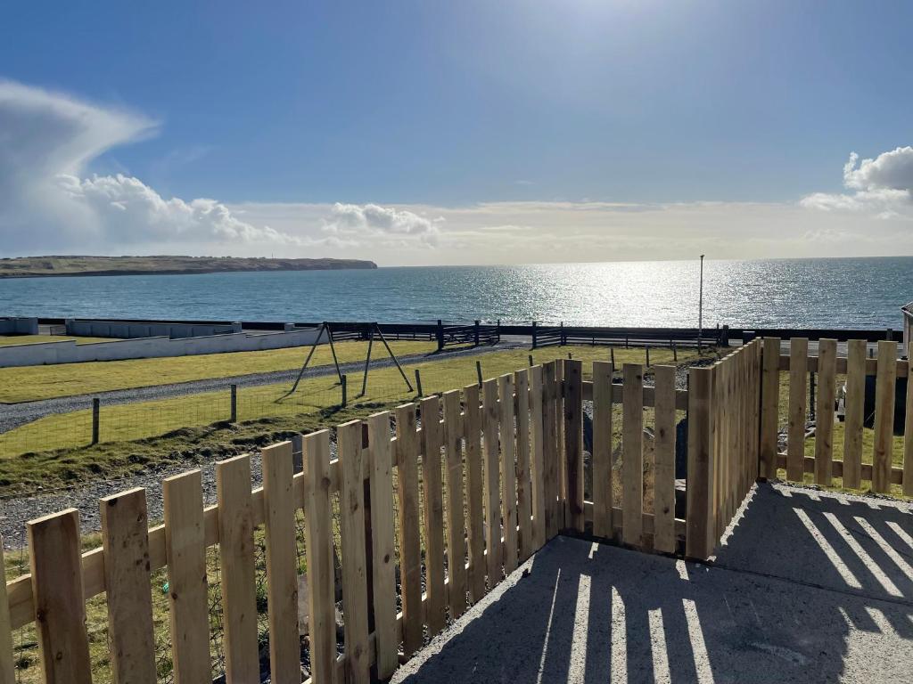 a wooden fence with a view of the ocean at Holmview apartment in Stornoway