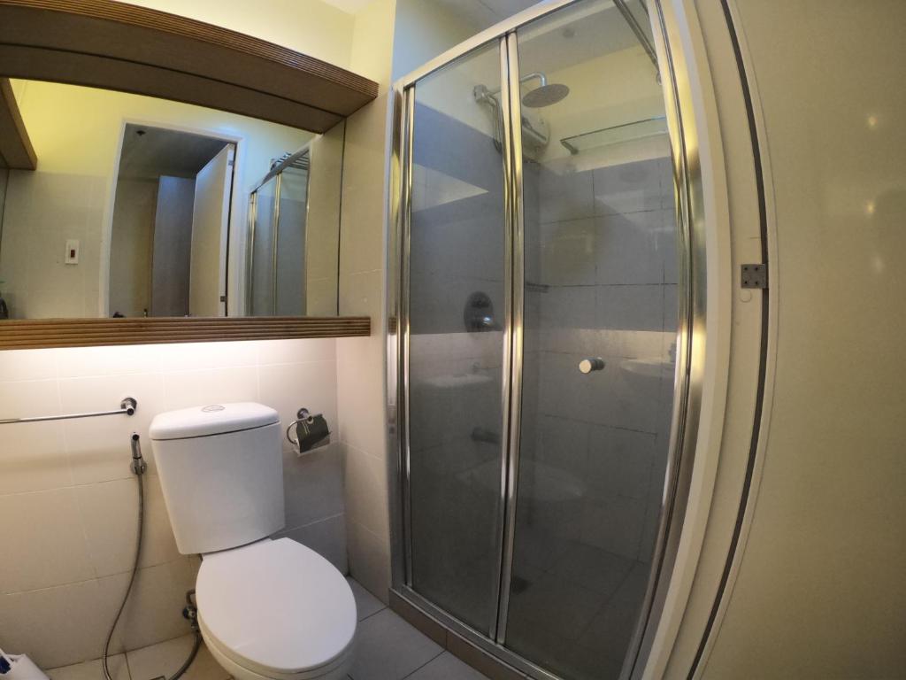 een badkamer met een toilet en een glazen douche bij Breezy Nest Staycation at Wind Residences Tagaytay in Tagaytay