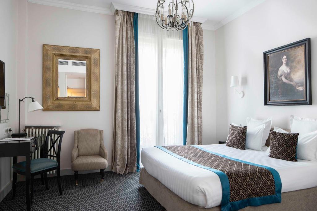 Habitación de hotel con cama, escritorio y silla en Bradford Elysées - Astotel, en París