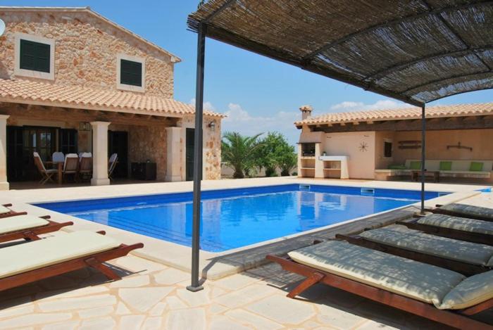 a villa with a swimming pool and a house at Finca Poas in Es Llombards