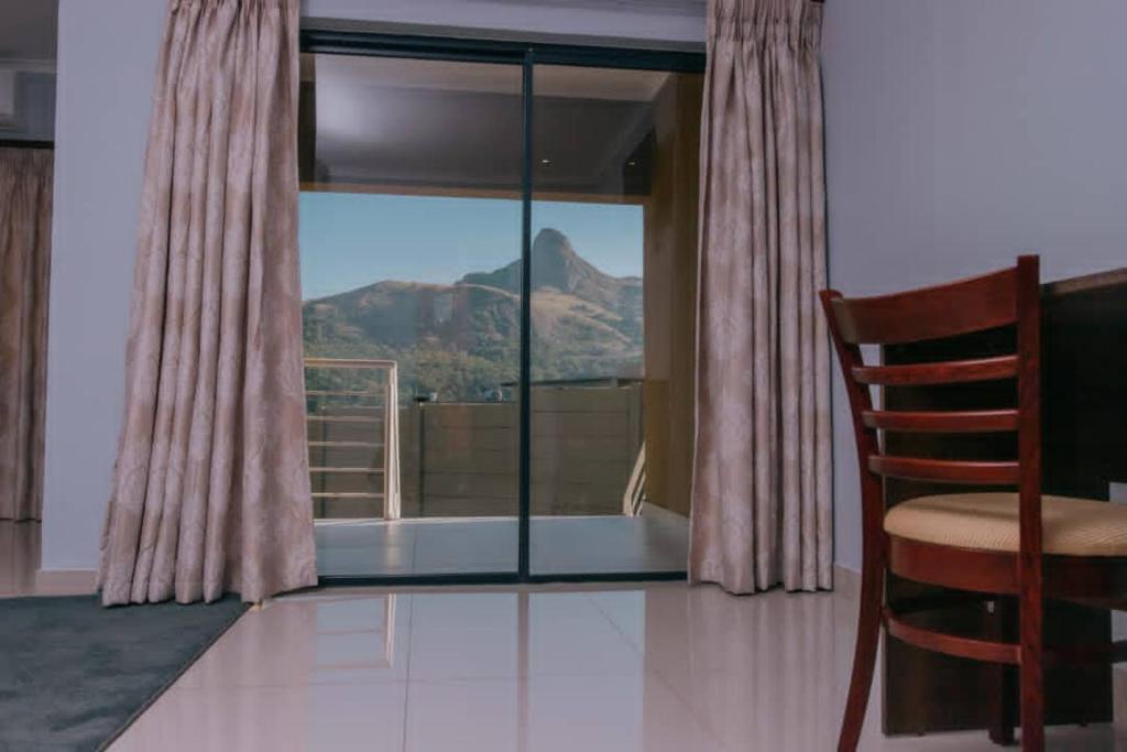 Habitación con silla y ventana con vistas a la montaña. en Mantenga Hillview en Ezulwini