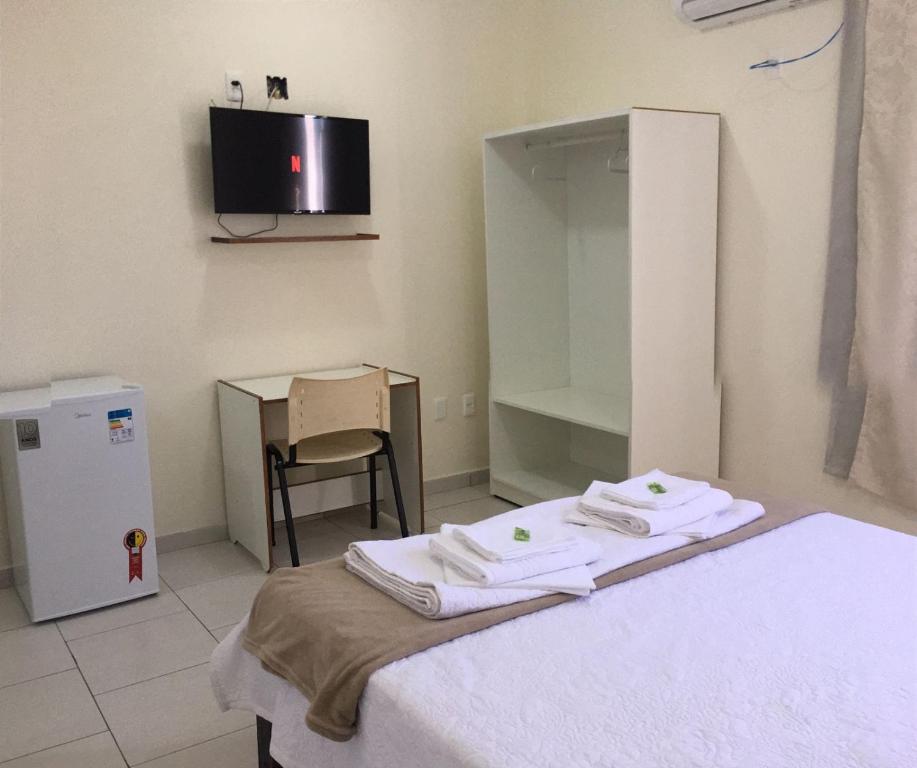 Una habitación con una cama, una mesa y un televisor. en Riachuelo Hotel, en Resende