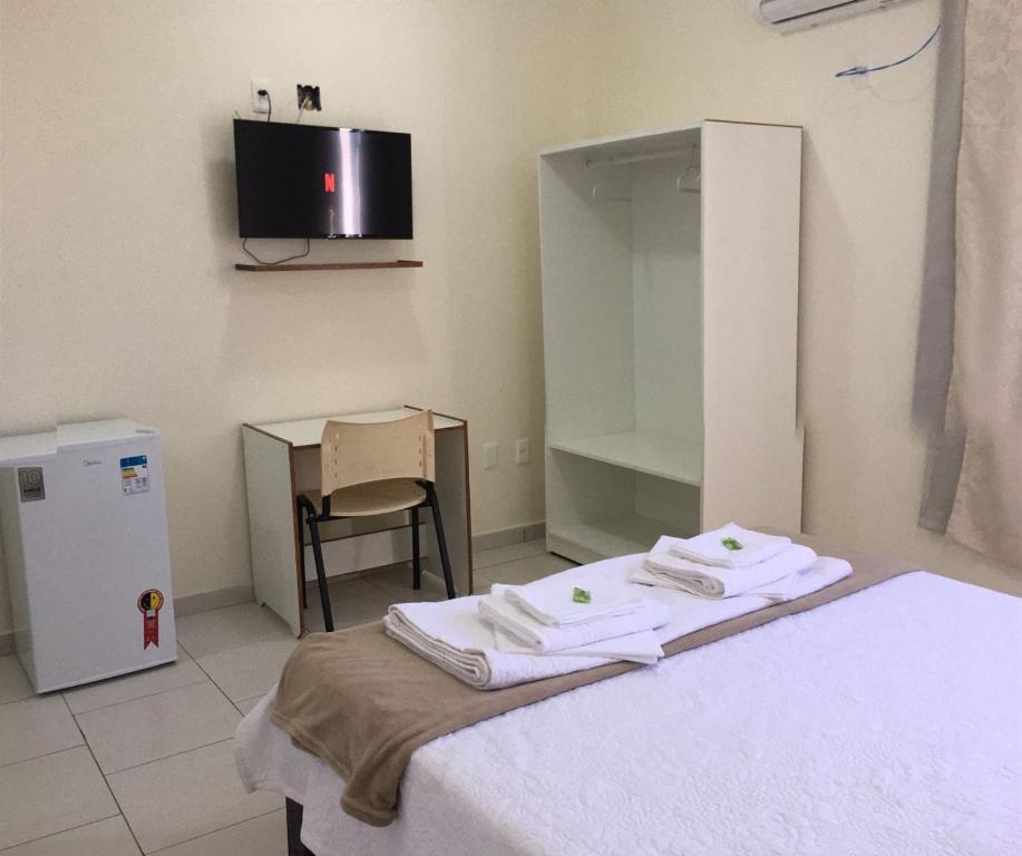 a room with a bed and a table and a tv at Riachuelo Hotel in Resende