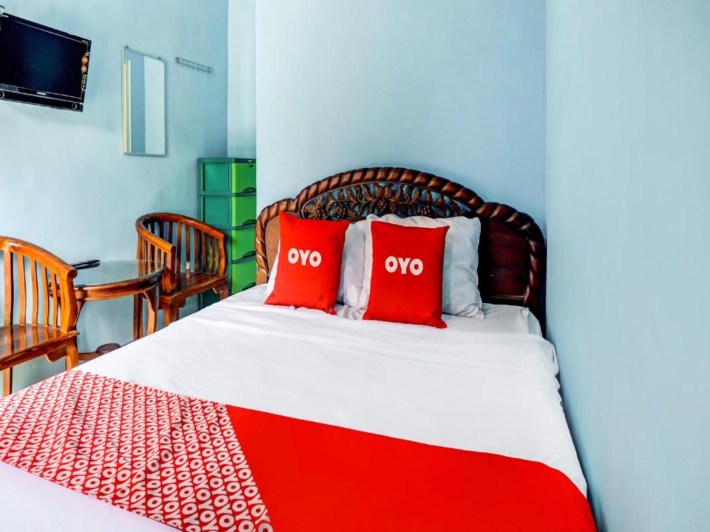 a bedroom with a bed with two red pillows at OYO Life 90879 Ara Predator Funpark in Batu