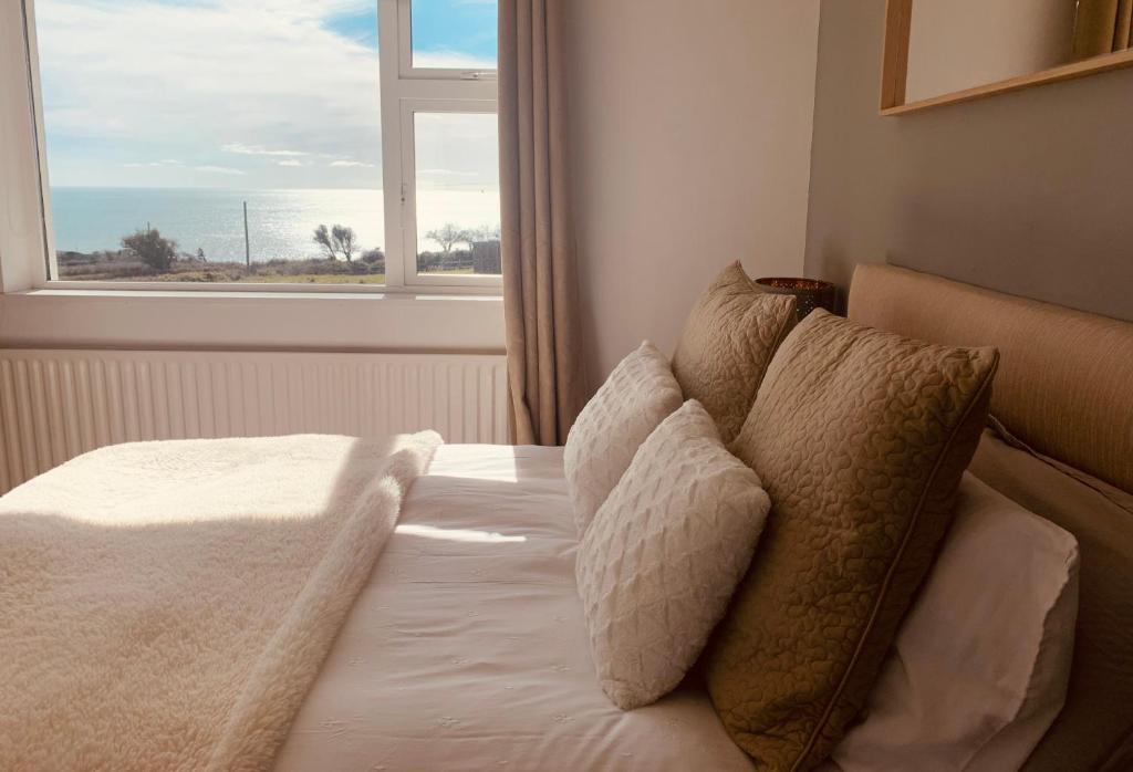 1 dormitorio con cama con almohadas y ventana en Follies Suites Ballyvoile, en Dungarvan